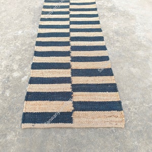 May include: A black and natural jute striped rug. The rug is woven with alternating black and natural jute stripes. The rug is approximately 2.5 feet wide and 8 feet long.