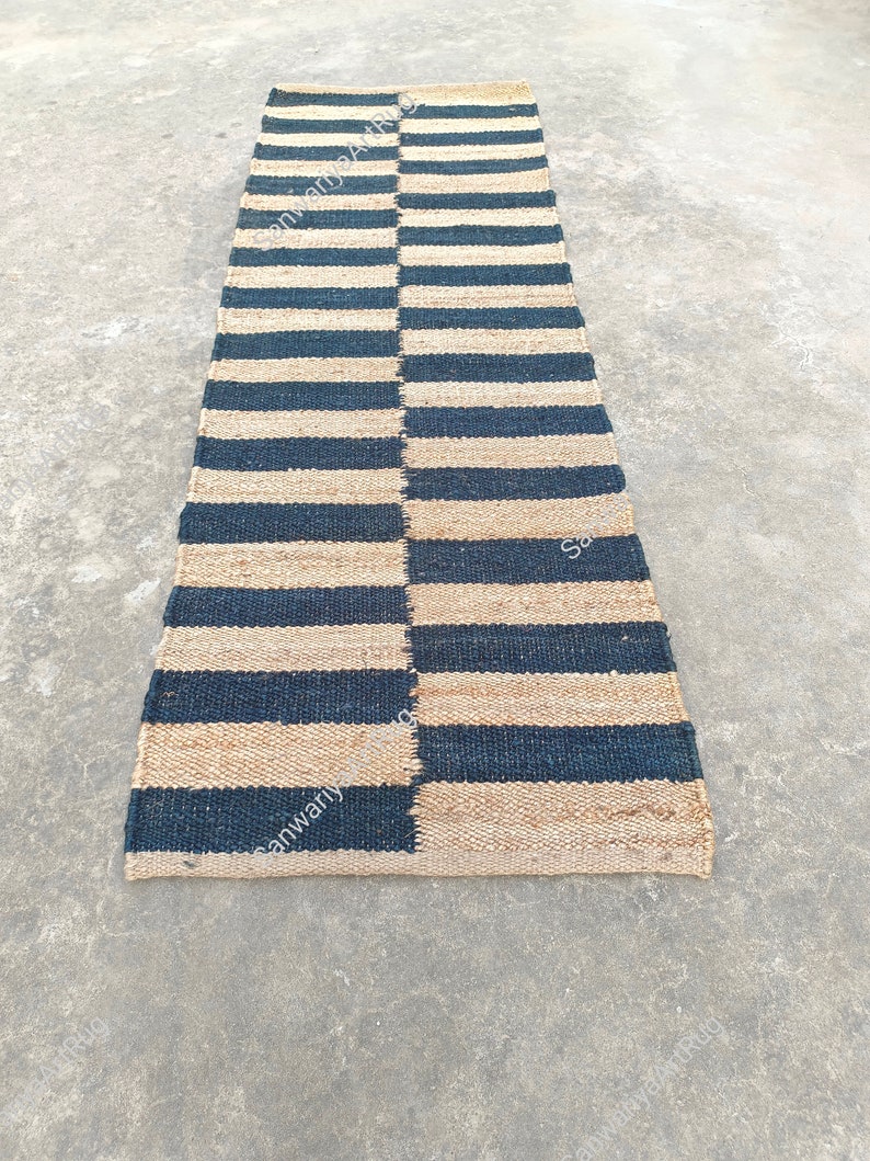 May include: A black and natural jute striped rug. The rug is woven with alternating black and natural jute stripes. The rug is approximately 2.5 feet wide and 8 feet long.