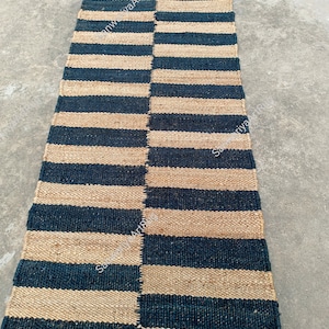 May include: A striped jute rug with alternating black and natural colored stripes. The rug is woven with a simple pattern and has a natural, rustic look.