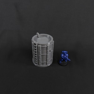 Könnte beinhalten: Ein graues 3D-gedrucktes Modell einer zylindrischen Struktur mit einer Leiter und einem Rohr oben. Die Struktur ist etwa 10 cm hoch und 5 cm im Durchmesser. Das Modell befindet sich auf einem schwarzen Hintergrund.