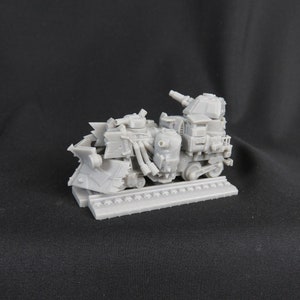 May include: A gray, 3D printed model of a futuristic, heavily armed train. The train has a large, armored front with a blade, a turret on top, and several pipes and other details. The train is on a track and appears to be ready for battle.