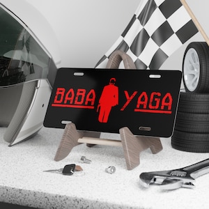 May include: Black license plate with a red silhouette of a man and the text "BABA YAGA" in red.