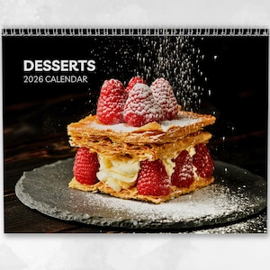 May include: A 2026 calendar featuring a layered dessert with fresh raspberries and powdered sugar. The calendar has a black background with the word "DESSERTS" and the year printed in white. The dessert sits on a dark gray plate.