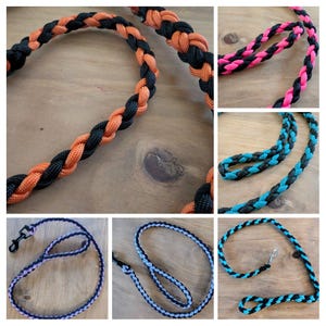May include: A collection of braided dog leashes in various color combinations. The leashes feature black and orange, pink and black, blue and black, and black and light blue. Each leash is made of a durable, woven material and includes a metal clasp.