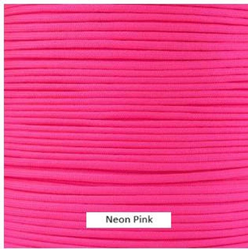 Puede incluir: Un carrete de paracord rosa ne&oacute;n, un tipo de cuerda de nylon resistente que se utiliza a menudo para manualidades y actividades al aire libre.