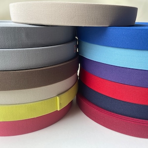 May include: A stack of different colored elastic bands, including beige, gray, brown, white, yellow, red, blue, and purple.