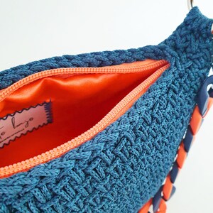 Bolso azul vaquero mediano, tipo baguette o bolso de hombro, tejido a crochet, hecho a mano, con asa acrílica azul y naranja, forro interior de tela satén naranja y cierre de cremallera.