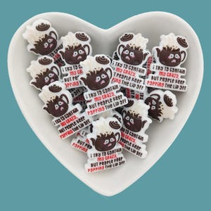 May include: A collection of brown and white ceramic teapots with a humorous saying on each: "I try to contain my crazy, but people keep popping the lid off".