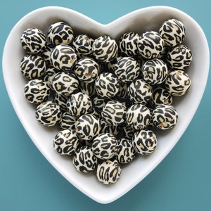 May include: A white bowl filled with black and brown silicone beads with a leopard print pattern.