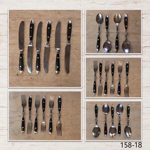May include: A collection of stainless steel flatware featuring black handles with silver rivets. The set includes knives, forks, and spoons arranged in five separate groupings. The text 158-18 is visible in the bottom right corner of the image.