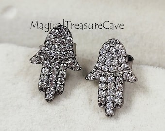 May include: A pair of black hamsa hand earrings with clear cubic zirconia stones. The earrings are in a small jewellery box.