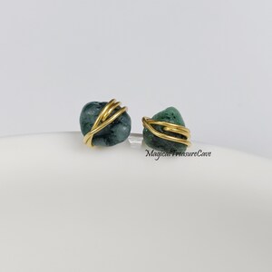 May include: A pair of earrings featuring green gemstone wrapped in gold wire. The earrings are small and delicate, perfect for everyday wear.