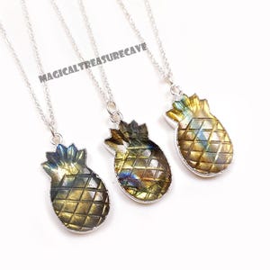 May include: Three pineapple-shaped pendant necklaces with silver chains. The pendants are carved from a stone with a mix of gold, blue, and green hues. The text "MAGICALTREASURECAVE" is visible in the image.