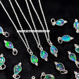 May include: Silver necklaces with teardrop-shaped pendants featuring iridescent opal stones. The pendants are accented with small silver details. The text "MAGICALTREASURECAVE" is visible in the background. The necklaces are displayed on a black surface.