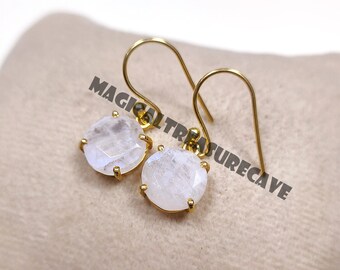 May include: A pair of gold dangle earrings with round, white moonstone gemstones. The earrings have a simple, elegant design.