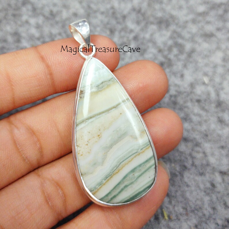 May include: A silver pendant with a teardrop-shaped green and white agate stone. The stone has a layered pattern with shades of green, white, and brown.
