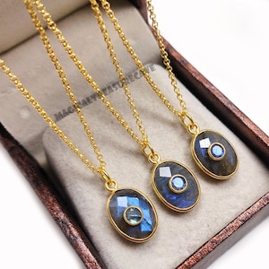 Peut inclure: Trois colliers dorés avec des pendentifs ovales. Chaque pendentif contient une pierre précieuse bleue facettée dans un cadre doré. Les colliers sont présentés dans une boîte marron. Le texte "MAGICALTREASURECAVE" est visible.