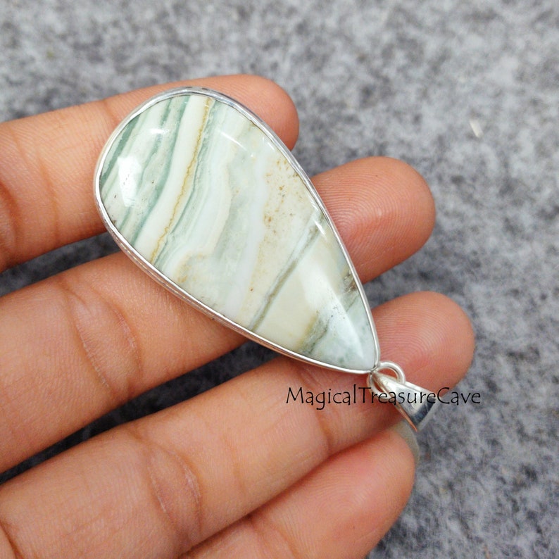 May include: A silver pendant with a green and white agate stone. The stone has a teardrop shape and is set in a silver bezel. The pendant is on a silver chain.