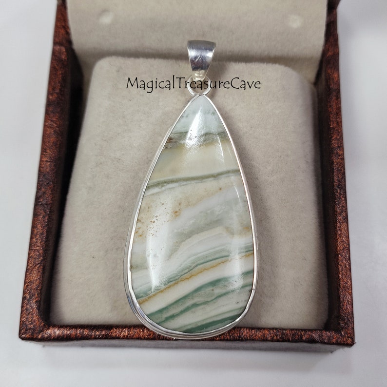 May include: A silver pendant with a teardrop-shaped green and white agate stone. The stone has a layered pattern and is set in a silver bezel.