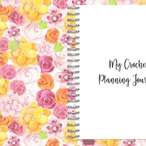 May include: A floral patterned journal with a white cover and a silver spiral binding. The cover reads "My Crochet Planning Journal".