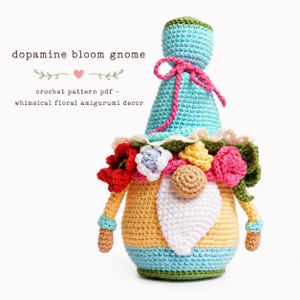 A vibrant crochet flower gnome designed as a summer bouquet. Cute handmade amigurumi gnome with pink and yellow blossoms. PDF crochet pattern design for whimsical home decor