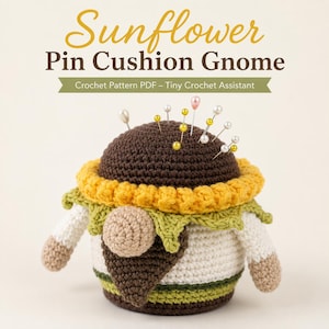 May include: A crochet gnome pin cushion with a dark brown top, yellow sunflower petals, and a green leaf collar. The gnome has a beige nose, a dark brown beard, and a white body with green stripes. Several sewing pins are stuck in the top.