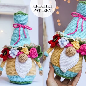 May include: A handmade crochet gnome doll with a light blue hat tied with pink string, a yellow and blue body, and a white beard. The gnome is adorned with colorful crochet flowers and the text "CROCHET PATTERN".