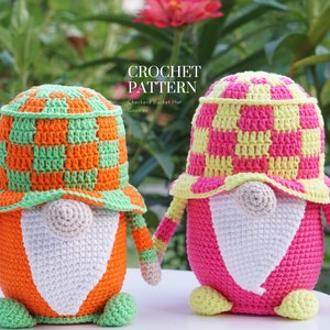 May include: Two crochet gnomes with checkered bucket hats. One gnome is orange and green, the other is pink and yellow. The gnomes have white beards and are holding hands. The text "CROCHET PATTERN" is at the top.