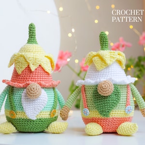 May include: Two crocheted gnomes with yellow flower hats, green and orange bodies, and white beards. The gnomes are sitting on a white surface. CROCHET PATTERN text is visible in the top right corner of the image.