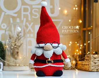 May include: Crochet pattern for a Christmas gnome. The gnome is wearing a red hat, a white beard, and a black belt. The gnome is holding a red bag. The pattern is called "Christmas Gnome".