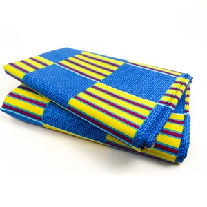 Könnte beinhalten: Zwei Stoffstücke, die zusammengelegt sind. Der Stoff ist gelb, blau und burgunderrot mit einem geometrischen Muster.