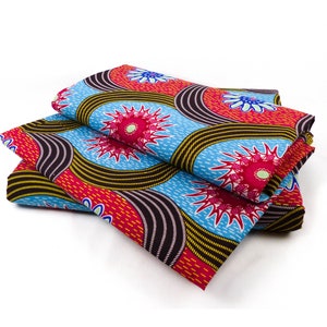 Könnte beinhalten: Ein Stapel bunter Stoffe mit einem sich wiederholenden Muster aus blauen, roten und gelben Kreisen mit stilisierten Blumendesigns. Der Stoff ist dreifach gefaltet.