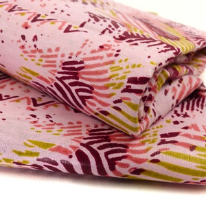 Può includere: Tessuto rosa con un motivo astratto colorato in tonalità di rosa, rosso e giallo. Il tessuto è piegato a metà.