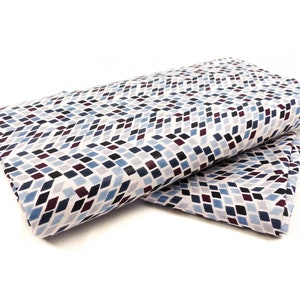 Könnte beinhalten: Zwei gefaltete Stoffstücke mit einem geometrischen Muster aus kleinen blauen, weißen und burgunderfarbenen Quadraten. Der Stoff hat einen weißen Hintergrund und die Quadrate sind diagonal angeordnet.