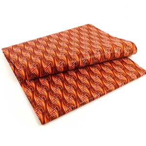 Könnte beinhalten: Zwei Stücke orangefarbenes und braunes gemustertes Stoff, die zusammengelegt sind. Der Stoff hat ein wellenförmiges Muster.