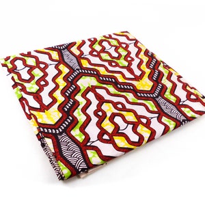 Könnte beinhalten: Ein gefalteter Stoff mit weißem Hintergrund und einem geometrischen Muster in Rot, Grün und Schwarz.