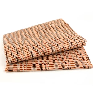 Könnte beinhalten: Zwei Stücke braunes und weißes Geschenkpapier, das zusammengelegt ist. Das Papier hat ein welliges, gestreiftes Muster.