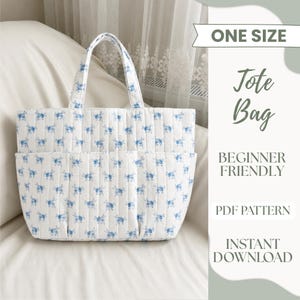 May include: A white quilted tote bag with a blue floral pattern, featuring two top handles and exterior pockets. The image includes text: ONE SIZE, Tote Bag, BEGINNER FRIENDLY, PDF PATTERN, INSTANT DOWNLOAD.