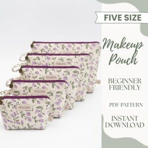 May include: A set of five makeup pouches in different sizes, adorned with a cream-coloured floral design with purple flowers and green leaves. Each pouch has a zip closure and a small label with the brand name. The image also includes text that says "Five Size" and "Makeup Pouch".