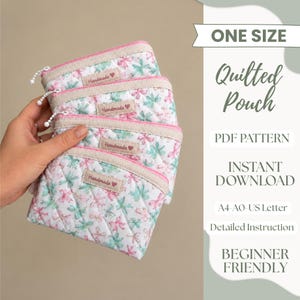 Può includere: Una pila di tre pochette trapuntate in tessuto bianco con motivo floreale rosa e verde, cerniere rosa e un'etichetta beige con la scritta Handmade e un cuore. Il testo a destra riporta ONE SIZE, Quilted Pouch, PDF PATTERN, INSTANT DOWNLOAD, A4-A0-US Letter, Detailed Instruction, BEGINNER FRIENDLY.