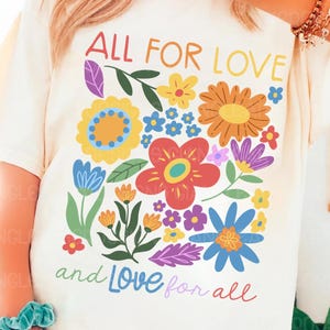 May include: A white t-shirt with a floral design and the text "All for Love and Love for all".