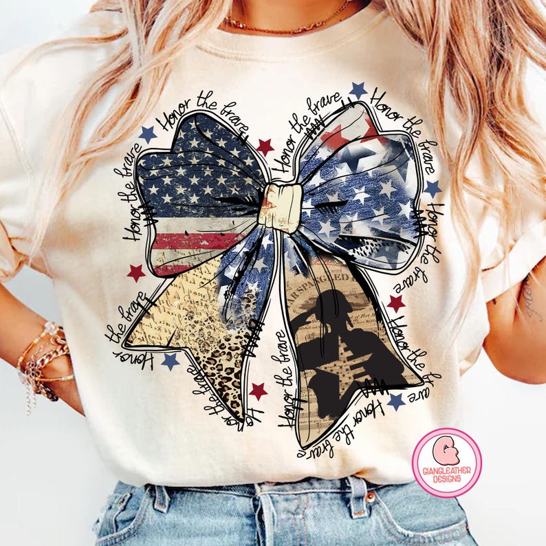 May include: A white t-shirt with a large bow made of an American flag print. The bow is surrounded by the text "Honor the brave" repeated multiple times.