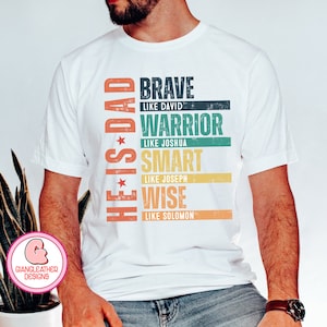 May include: White t-shirt with the text "HE IS DAD" in orange and red, and the words "BRAVE, WARRIOR, SMART, WISE" in different colors. The shirt also includes the phrases "LIKE DAVID, LIKE JOSHUA, LIKE JOSEPH, LIKE SOLOMON."