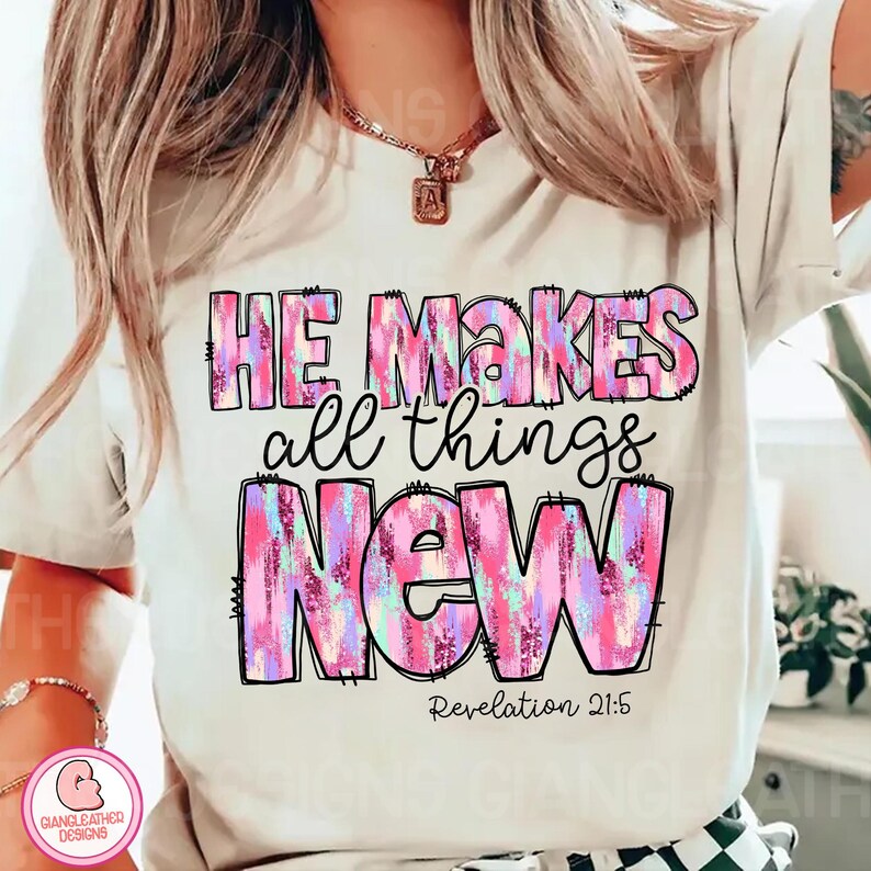 May include: White t-shirt with a pink, blue, and purple graphic print that says "He makes all things new" with the Bible verse "Revelation 21:5" underneath.