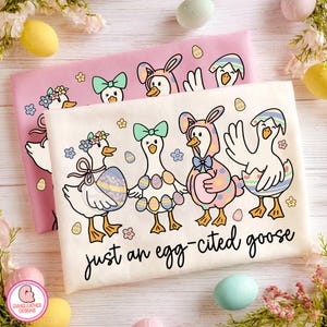 May include: Two t-shirts, one pink and one off-white, featuring an Easter-themed design. The design includes cartoon geese dressed in Easter attire, with the text "just an egg-cited goose". The geese are decorated with Easter eggs and bows.