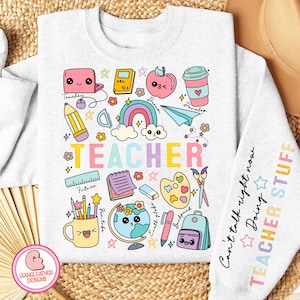 Puede incluir: Una sudadera gris claro con un diseño colorido de útiles escolares y la palabra "TEACHER" en letras arcoíris. La manga tiene el texto "Can't talk right now Doing TEACHER STUFF" en letras negras.