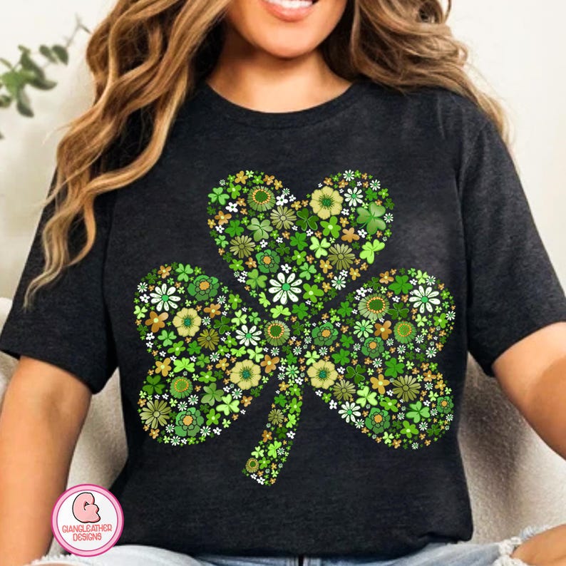May include: Dark gray t-shirt featuring a floral shamrock design. The shamrock is composed of various green and white flowers and leaves, with a heart-shaped top leaf. A St. Patrick's Day themed graphic tee.