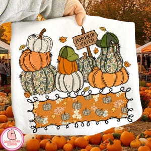 May include: White fabric with a fall-themed design featuring stacked pumpkins in orange, white, and camouflage patterns. The design includes a sign that reads "Pumpkin Patch" and a border with pumpkins and floral accents.