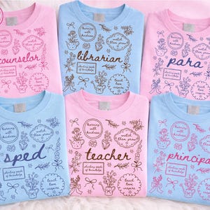 May include: Six crew neck t-shirts in pink and blue. Each shirt has a different design, featuring the words "counselor", "librarian", "para", "sped", "teacher", and "principal", accompanied by floral and botanical illustrations.