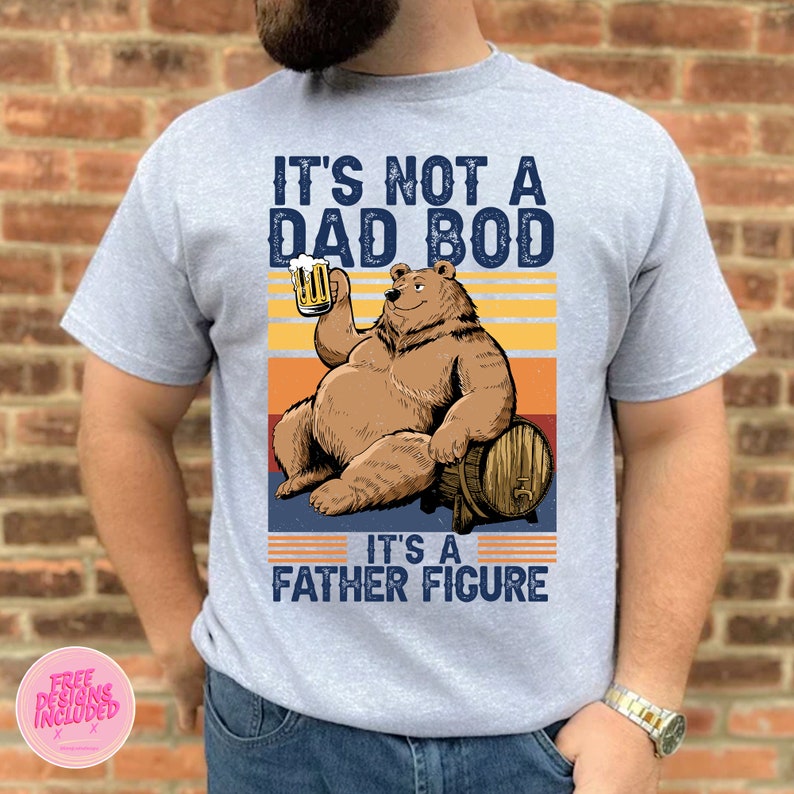 May include: A gray t-shirt with a vintage-style graphic of a bear holding a beer and sitting on a barrel. The text on the shirt reads "It's not a dad bod, it's a father figure."